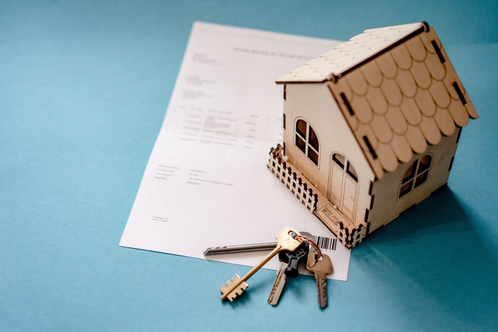 15 Common Real Estate Questions 10 wooden house and keyring on purchase paperwork - hire America's Finest Property Management