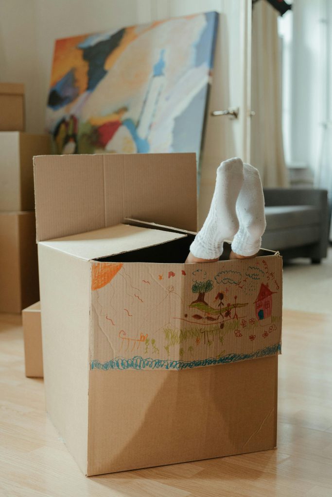 A child's sock feet poking out of the cardboard box they're playing in - Visit afinestpm.com.