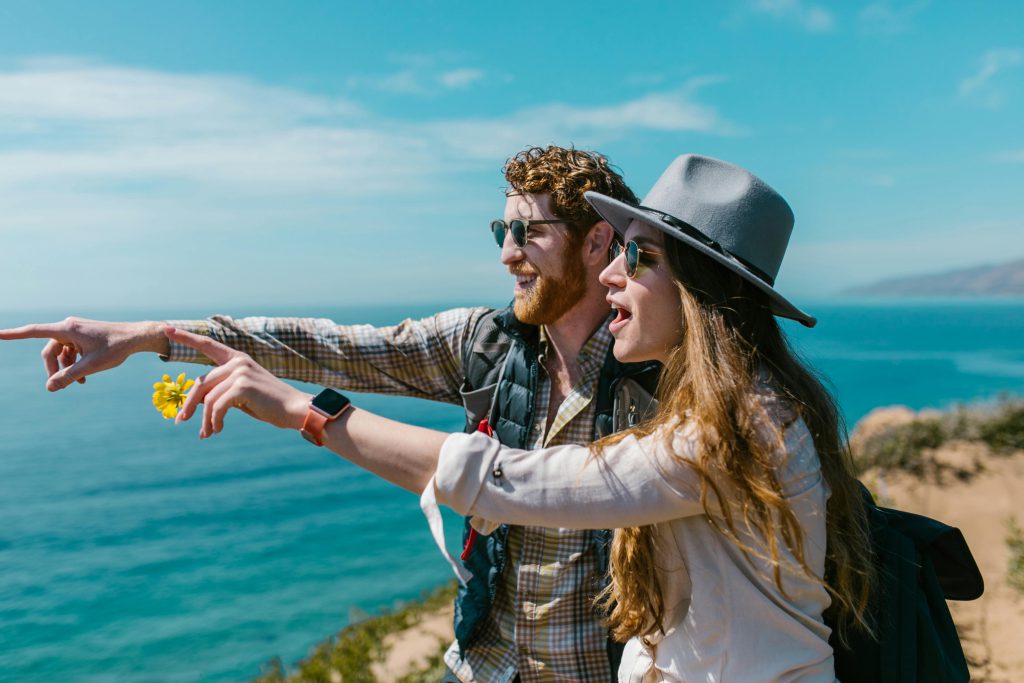 Man and woman pointing into distance on Southern California shore - visit afinestpm.com. 