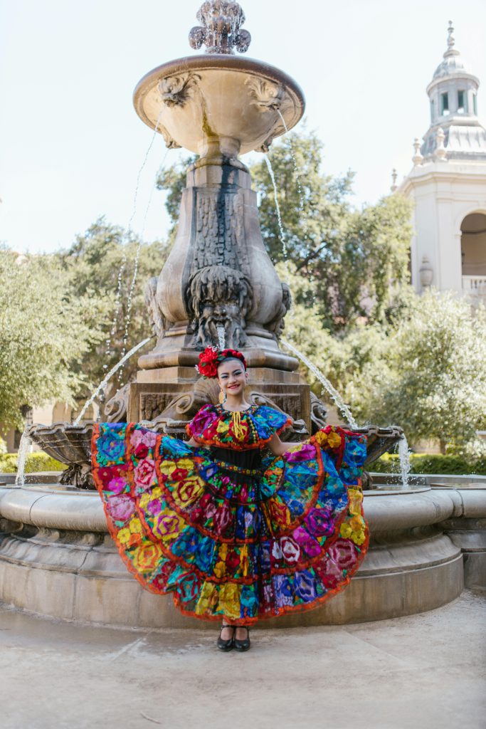 Dancer in colorful Latin American traditional dress posing in front of a fountain - visit afinestpm.com.