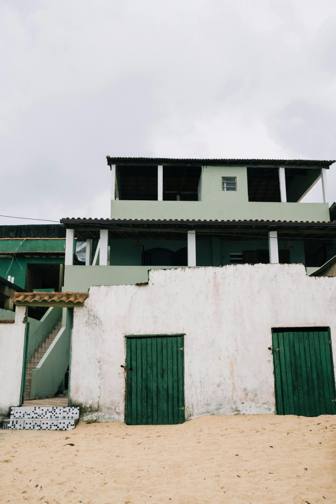 Weather-worn structure with green doors on beach - visit afinestpm.com. 