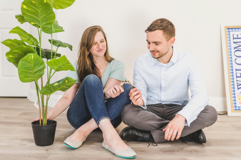 The Ultimate Guide to Renting in San Diego: Tips for Tenants and Landlords 7 A couple sitting cross-legged side by side holding keys. There's a fiddle leaf fig to the left. - Visit Afinestpm.com.